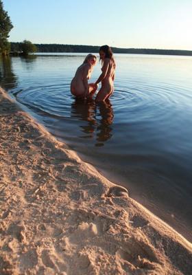 Dos jóvenes nudistas se divierten juntos en el lago